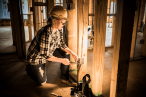 Female electrical technician installs a electrical outlet in a new build house.
