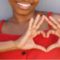African American woman making heart hands in celebration of American Heart Month 2021.