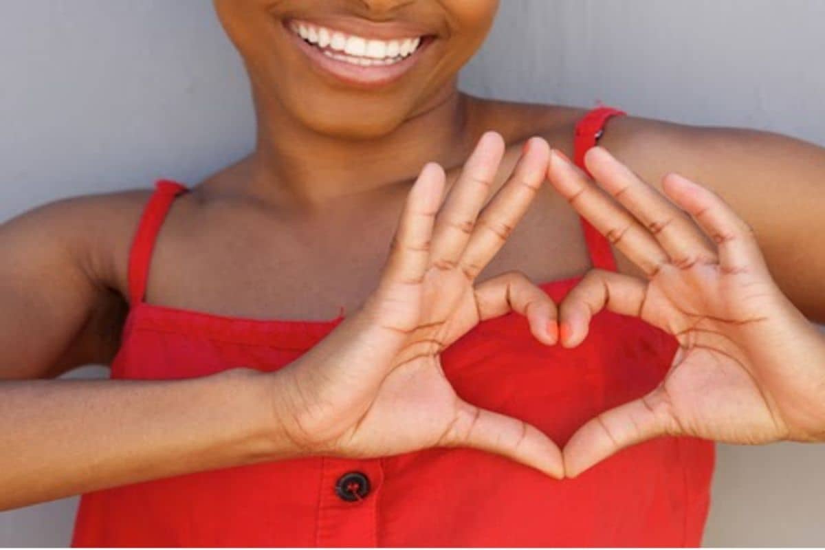 African American woman making heart hands in celebration of American Heart Month 2021.