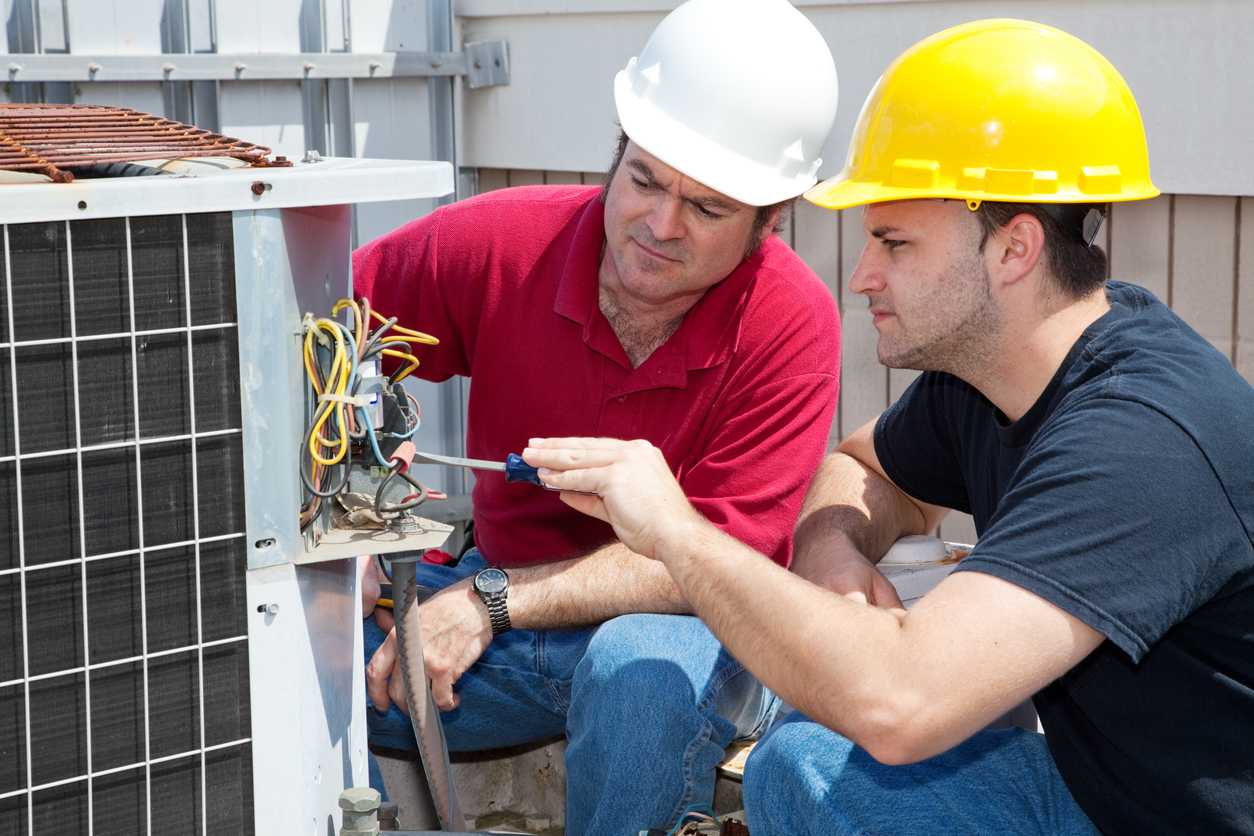 A student getting hands-on experience from an instructor during an HVAC