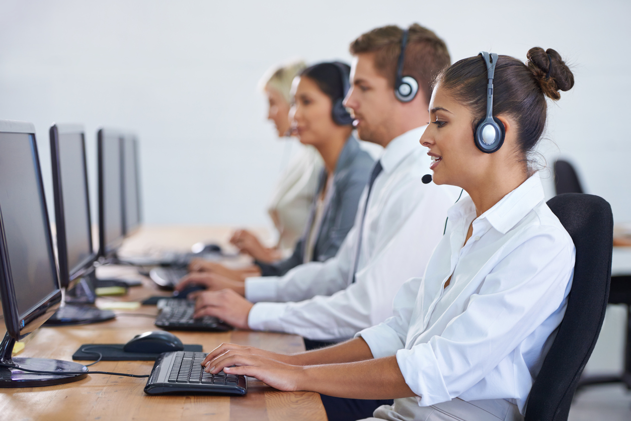 A row of computer support specialists taking phone calls to offer IT support.