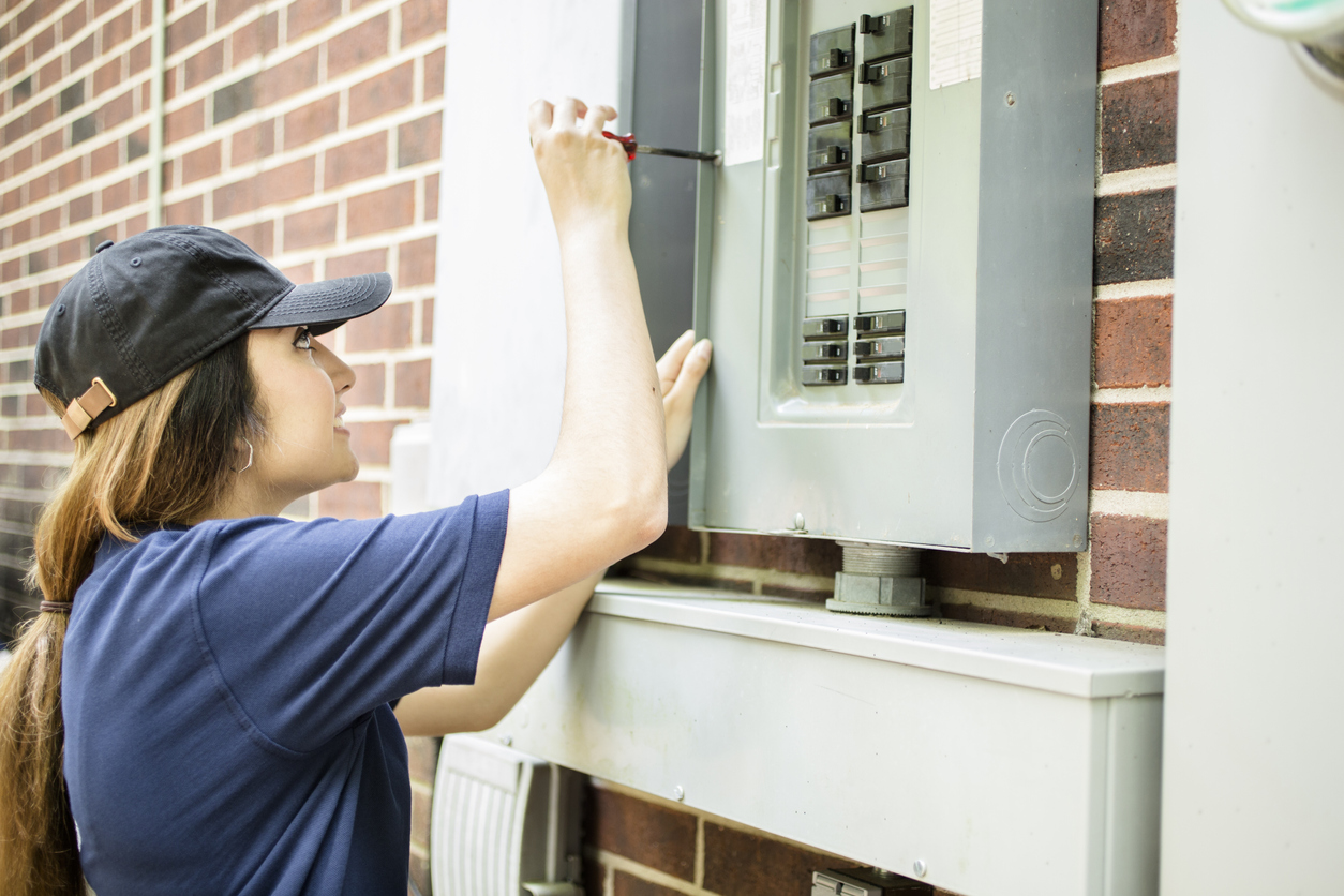 A female electrician, not an electrical technician, repairing a home breaker box.