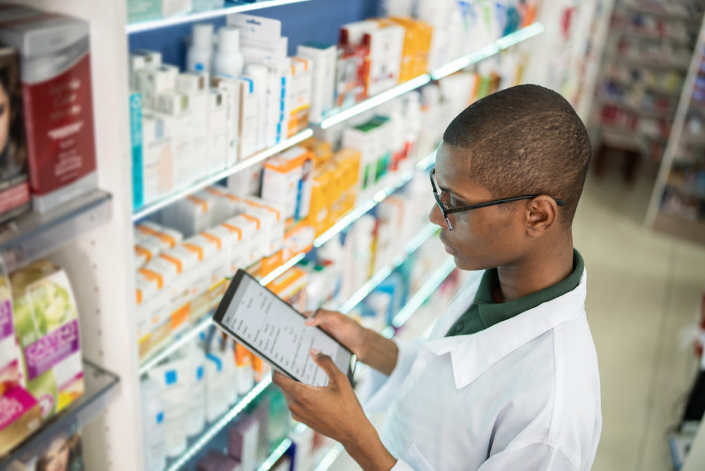 A pharmacist checking the shelves in a pharmacy after receiving their certifications upon pursuing education after high school. 