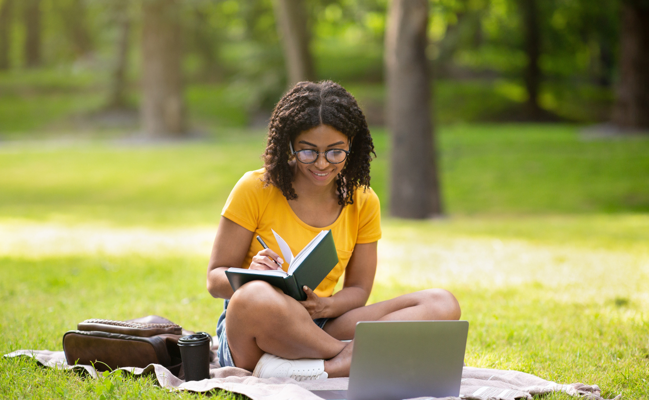 A female studying for a summer semester class in college while at the park.