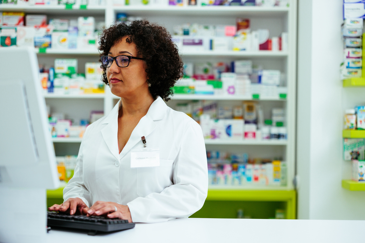 African American female pharmacist working at a drugstore and using a computer