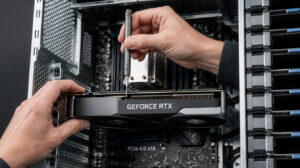 Technician using a screwdriver to install a graphics card inside an open desktop computer.